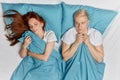 Serious scared man holding blancket looking at sleeping ginger girl Royalty Free Stock Photo