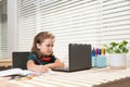 Serious school boy concentrated on drawing when sitting in class with laptop computer. Royalty Free Stock Photo