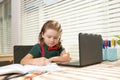 Serious school boy concentrated on drawing when sitting near laptop at home. Royalty Free Stock Photo