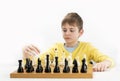 Serious schoolboy plays chess. Portrait of child during chess game. Isolated on white background Royalty Free Stock Photo