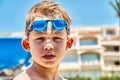 Serious schooler with goggles stands against hotel building