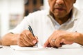 Serious senior man sitting on a library bench writing in his book. Royalty Free Stock Photo