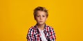 Serious seriously calm cute caucasian teenage boy looking at camera, isolated on yellow background