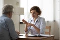 Serious skilled young female doctor explaining treatment to old patient.