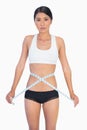 Serious slim woman measuring her waist