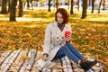 Serious smart young european red-haired lady in raincoat enjoy cup of hot drink from thermos, read book Royalty Free Stock Photo