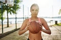 Serious sportive girl looking at camera while posing with basketball outdoors on a sunny day Royalty Free Stock Photo