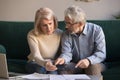 Serious stressed old couple looking at calculator feeling worried