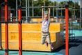 Boy hanging from the pull-up bar outdoors