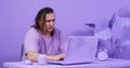 Serious student does coursework on laptop at table in room