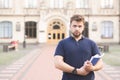 serious student stands with books in the hands of the university building and looks at the camera Royalty Free Stock Photo