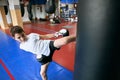 Serious sweaty boy kicking punching bag at sport center