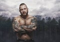 Serious tattooed male over dark forest