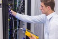 Serious technician using digital cable analyzer on server