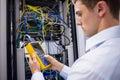 Serious technician using digital cable analyzer on server