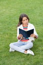 serious teen girl read book sitting on grass. reading book. reader girl with book outdoor Royalty Free Stock Photo