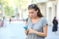 Serious teen texting on phone standing in the street