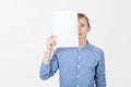 Serious Teenage boy holding blank sheet of paper covering half face . Man covering half face with blank sheet of paper for hiding Royalty Free Stock Photo