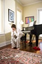 Serious teenage boy sitting on piano bench