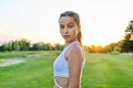 Serious teenage girl looking at the camera, in the park on lawn. Royalty Free Stock Photo