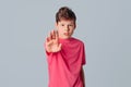 Serious teenager boy keeps palm raised makes restriction or denial gesture, asks to halt, blocks bad offer refuses something, gray