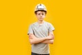 Serious teenager boy wears glasses and protective white helmet crossed his arms on chest. Child as a builder. Copy space