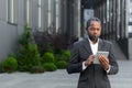 Serious thinking african american businessman using tablet computer, man in business suit mature reading news online Royalty Free Stock Photo