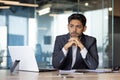 Serious thinking arab businessman at workplace, man sitting at desk with laptop in business suit, concentrating on Royalty Free Stock Photo