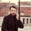 Serious thinking business man in fashion clothing talking on mobile phone on outdoors autumn background. Closeup Royalty Free Stock Photo