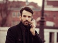 Serious thinking business man in fashion clothing talking on mobile phone on outdoors autumn background. Closeup Royalty Free Stock Photo