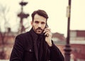 Serious thinking business man in fashion clothing talking on mobile phone outdoors autumn background. Portrait Royalty Free Stock Photo