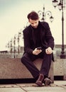 Serious thinking business man in fashion clothing texting sms looking on mobile phone in the hand outdoors autumn background Royalty Free Stock Photo