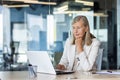 Serious thinking businesswoman working inside office with notebook, mature senior woman boss with gray hair at workplace Royalty Free Stock Photo
