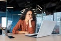 Serious thinking Latin American woman working inside office, businesswoman pondering complex decisions using laptop at