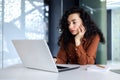 Serious thinking Latin American woman working inside office, businesswoman pondering complex decisions using laptop at