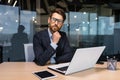 Serious thinking senior businessman working inside office using laptop, man in glasses solving problem, mature investor Royalty Free Stock Photo