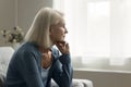 Serious thoughtful blonde senior lady sitting on couch at home Royalty Free Stock Photo