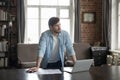 Serious thoughtful millennial business man standing at laptop and documents Royalty Free Stock Photo