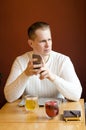 Serious thoughtful stylish man in casual white sweater, plans something while sits in cafeteria with tasty green tea, beverage,