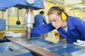 serious trainees focused on drilling metal piece with professional machinery