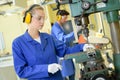 Serious trainees focused on drilling metal piece with professional machinery