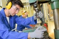 Serious trainees focused on drilling metal piece with professional machinery