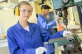 Serious trainees focused on drilling metal piece with professional machinery