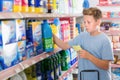 Serious tweenager boy looking household chemicals with shopping list Royalty Free Stock Photo