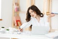 Serious well-dressed saleswoman talking on phone in office behind her desk and laptop computer. Copy space Royalty Free Stock Photo