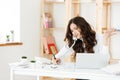 Serious well-dressed saleswoman talking on phone in office behind her desk and laptop computer. Copy space Royalty Free Stock Photo