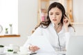 Serious well-dressed saleswoman talking on phone in office behind her desk and laptop computer. Copy space Royalty Free Stock Photo