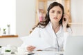 Serious well-dressed saleswoman talking on phone in office behind her desk and laptop computer. Copy space Royalty Free Stock Photo