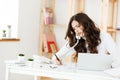 Serious well-dressed saleswoman talking on phone in office behind her desk and laptop computer. Copy space Royalty Free Stock Photo