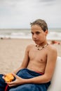 Serious wet boy holding apricot on the beach Royalty Free Stock Photo